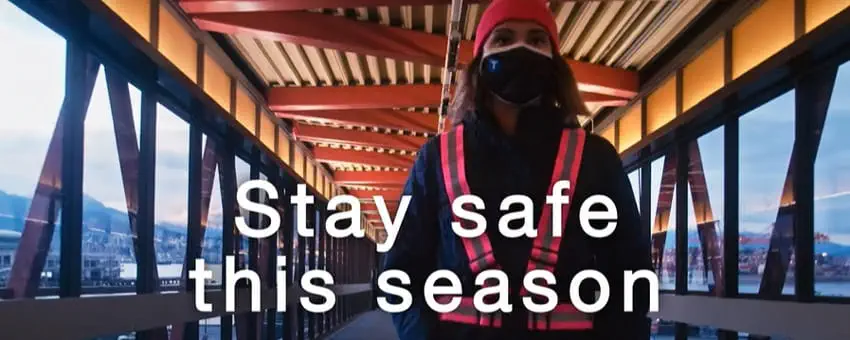 Passenger dressed warmly on SeaBus overpass with the words 'Stay safe this season' overlaid