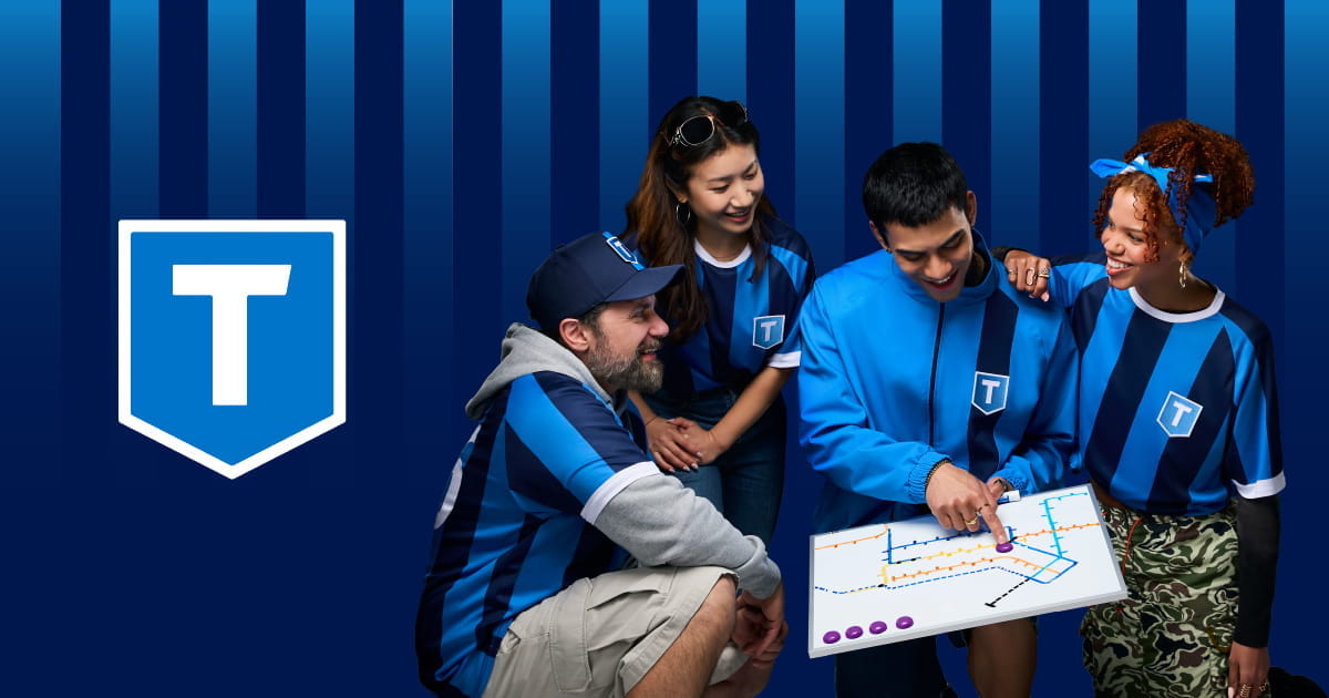 Three football fans wearing TransLink kits while looking at a transit map