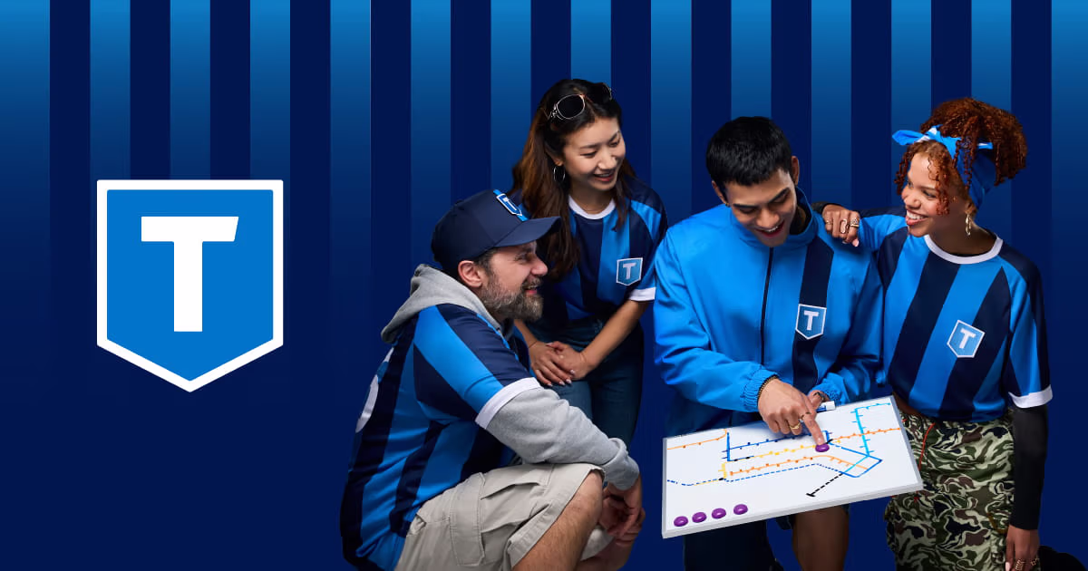 Three football fans wearing TransLink kits while looking at a transit map