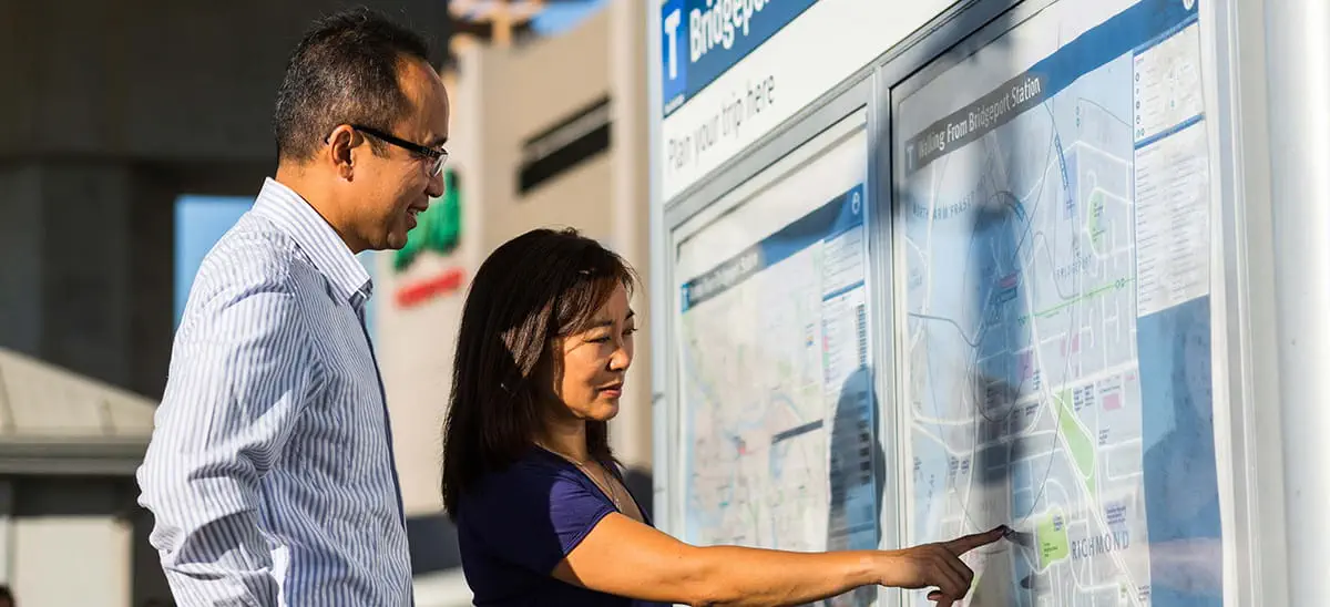 A man and woman pointing at a map at a bus exchange