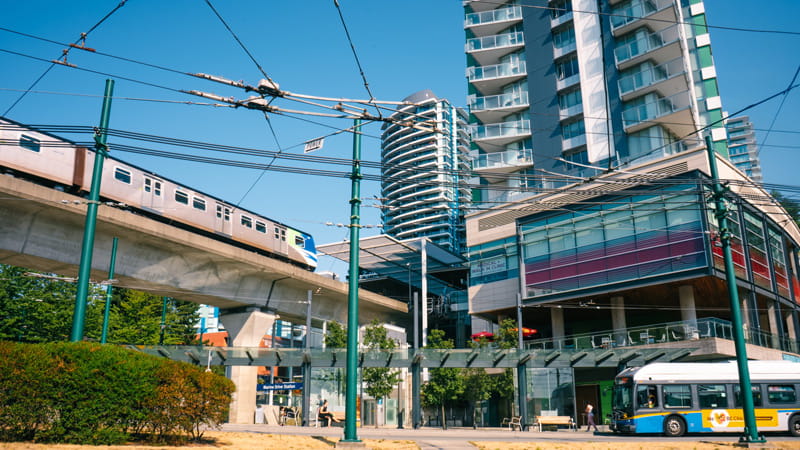 A train arrives at Marine Drive station while passengers wait for a bus at street level