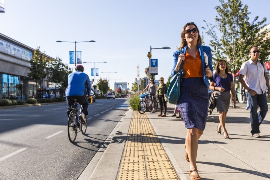 A woman holding business files while walking away from a transit bus stop