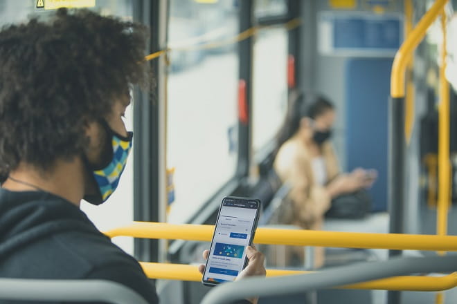 Masked customer uses phone on bus