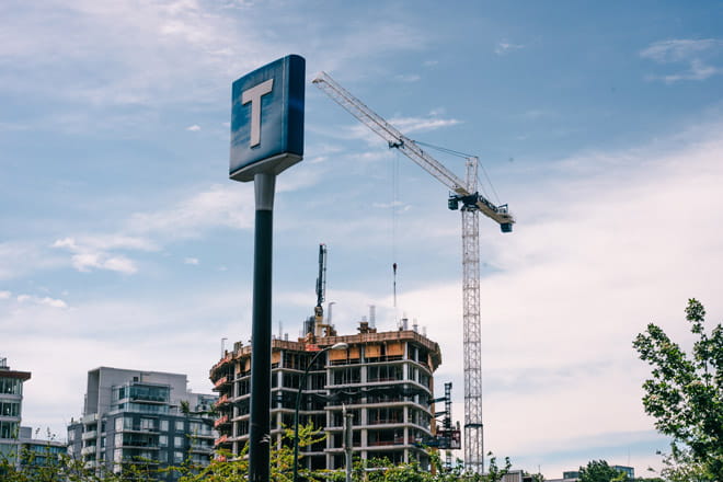 TransLink T logo signage with cranes and real estate development in background