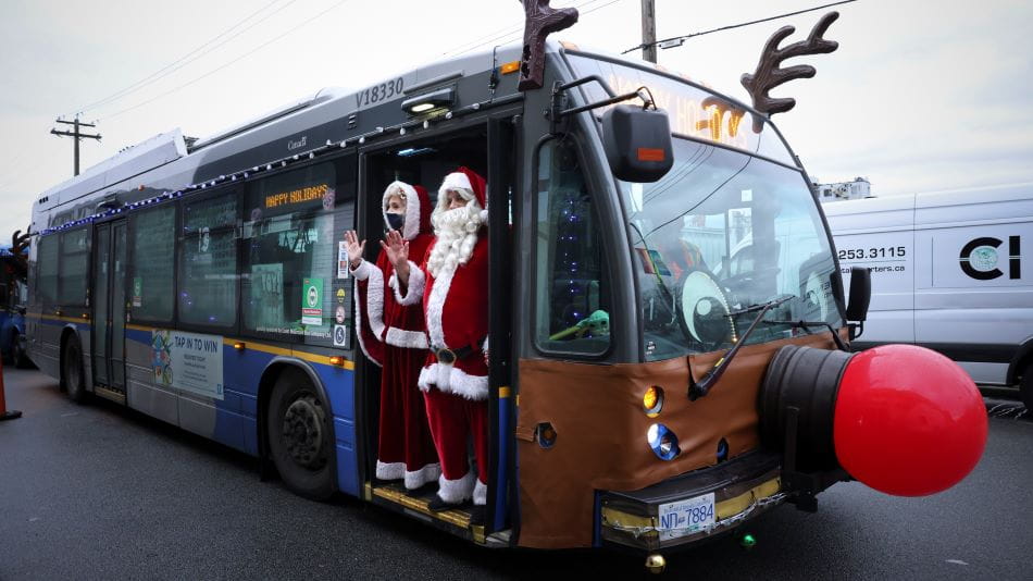 Santa and Mrs. Claus standing in front of Reindeer Bus.