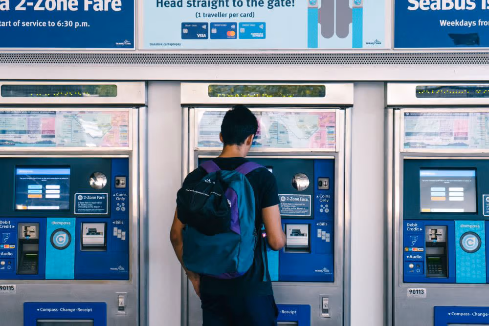 Back of male with backpack facing Compass Vending Machine at SkyTrain station