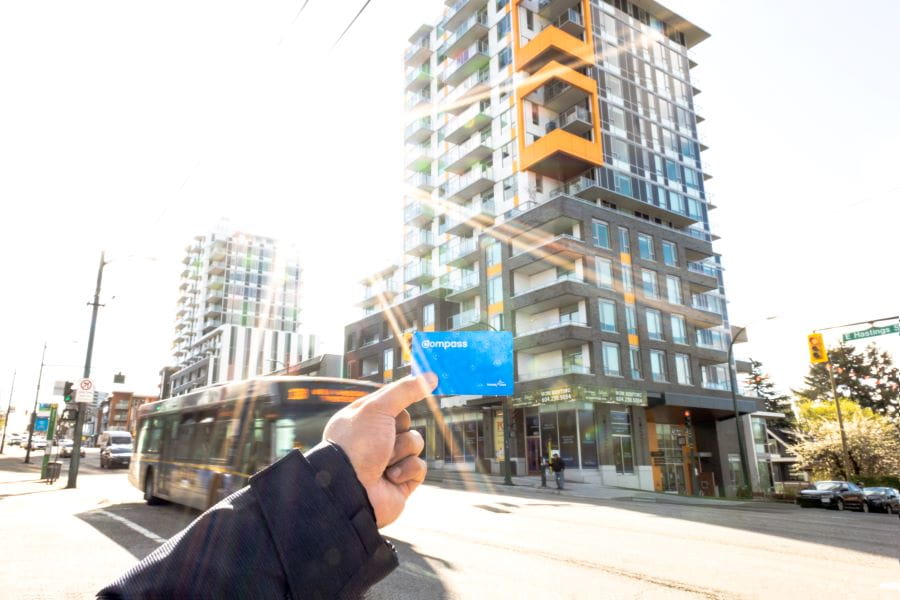 Hand holding Compass Card in foreground with bus and Yarrow residential building on Hastings St. in background.