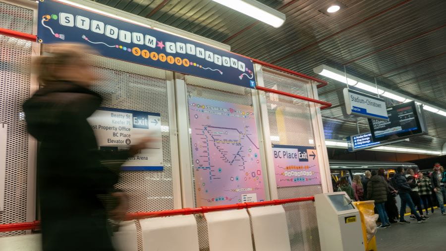 SkyTrain customers at Stadium-Chinatown Station with Taylor Swift-themed map in front.