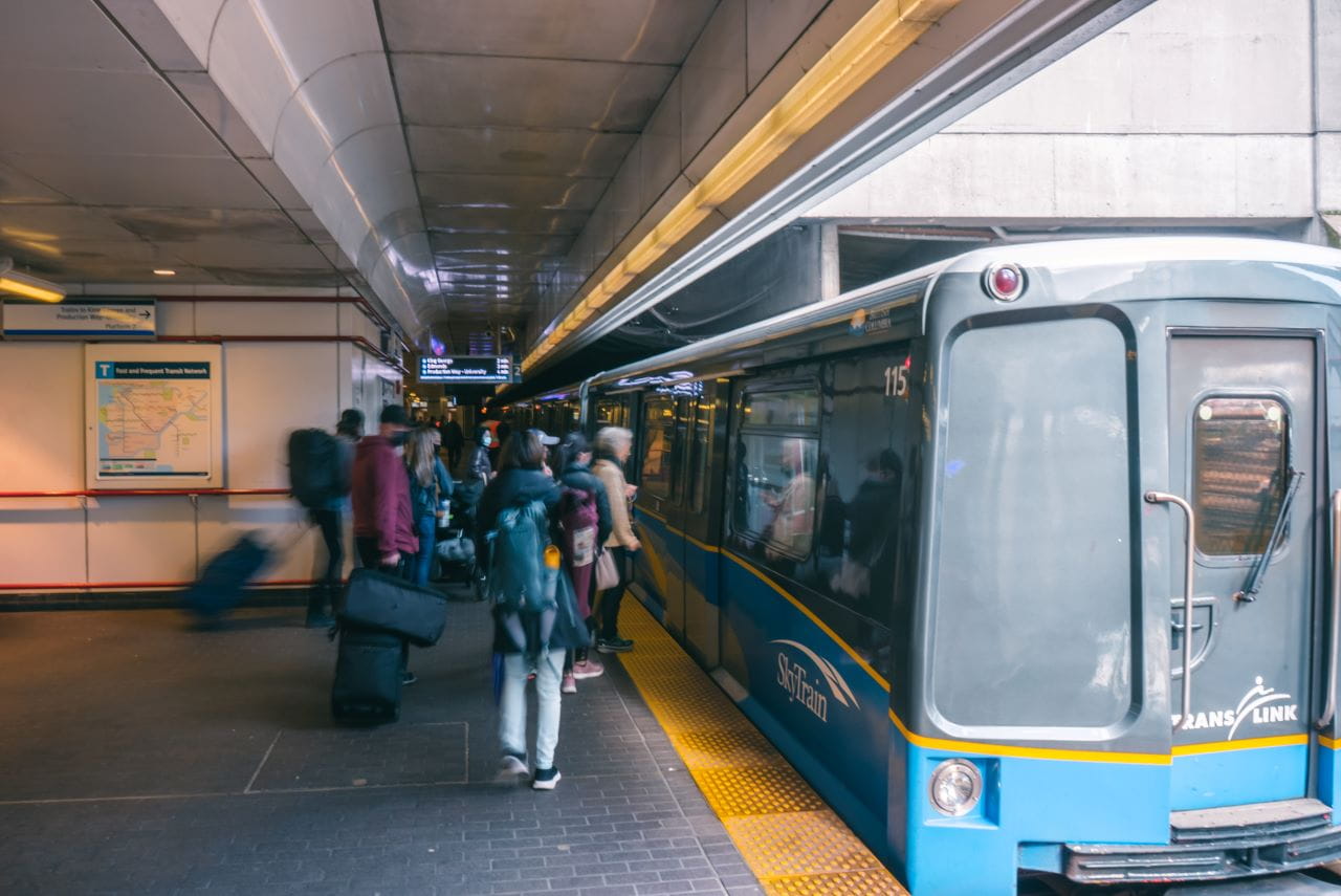 A busy SkyTrain station with customers moving to board a SkyTrain