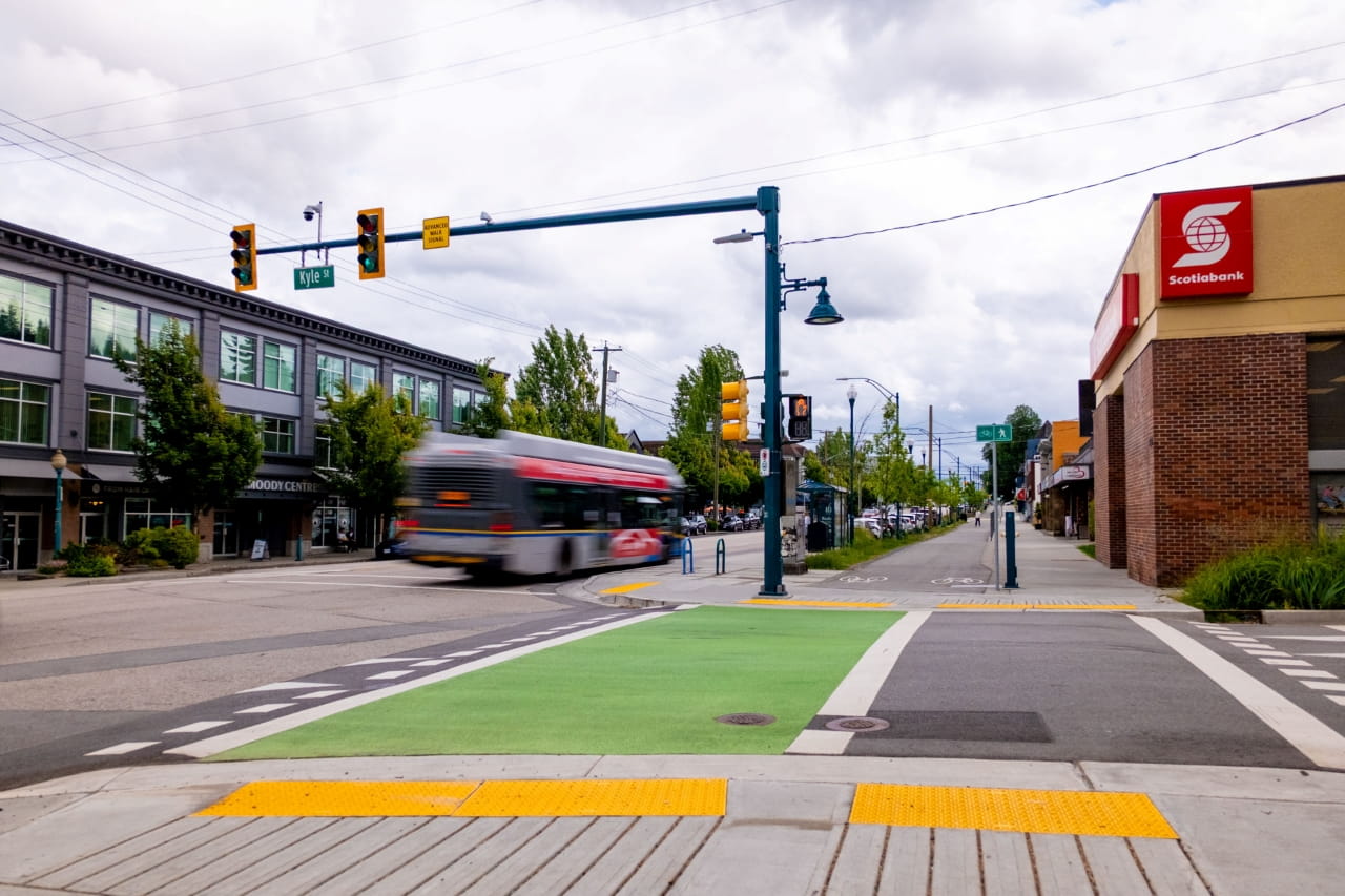 an intersection showing transit improvements, including a separated bike path, improved safety features for crosswalks and sidewalks
