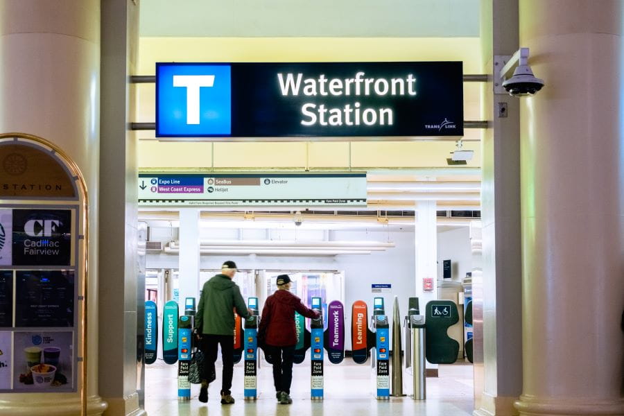 Entrance to Waterfront SkyTrain Station fare paid zone with senior couple walking through fare gates