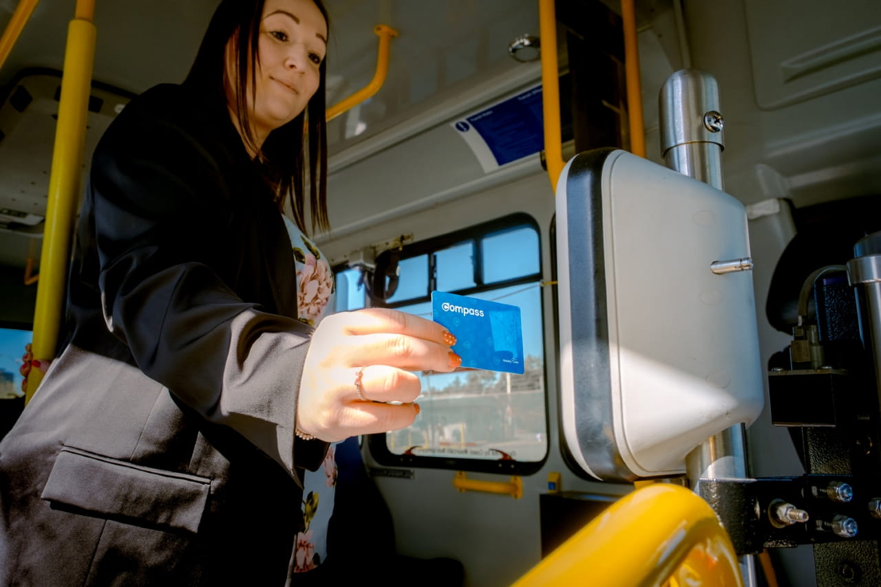 A professional woman is using her Compass Card to tap in to a bus