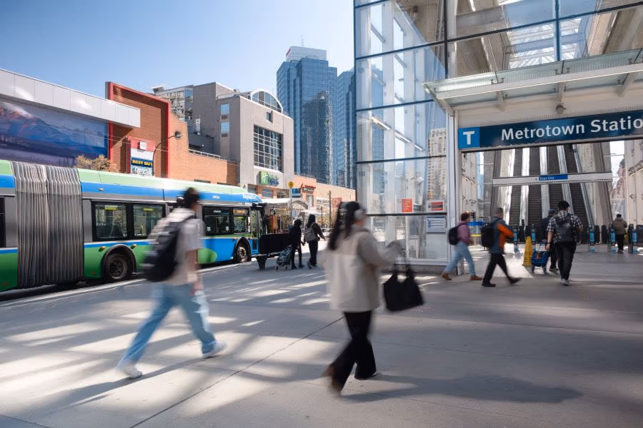 R2 RapidBus parked beside Metrotown Station with people walking toward stairs at station entrance