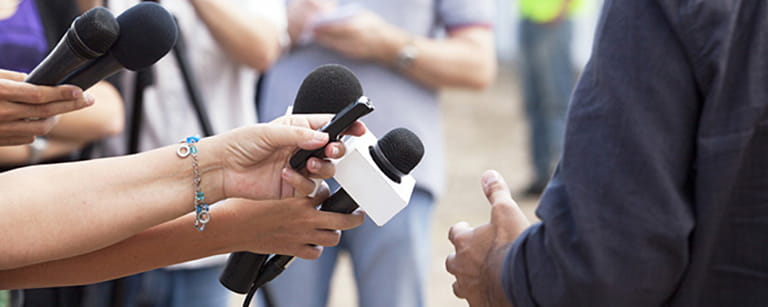 A couple of microphones pointing towards a public speaker